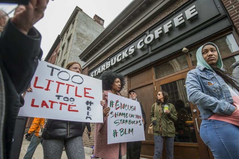 Protesters gather outside of a Starbucks in Philadelphia, Sunday, April 15, 2018, where two black men were arrested Thursday after employees called police to say the men were trespassing. The arrest prompted accusations of racism on social media. Starbucks CEO Kevin Johnson posted a lengthy statement Saturday night, calling the situation 