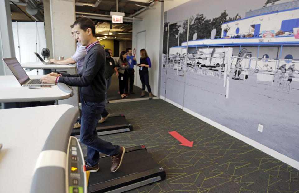 FILE- In this Dec. 3, 2015, file photo employees work at treadmill desks in the new Google Chicago Headquarter in Chicago. Goldman Sachs pinned a poll to its Twitter account asking what its employees should wear to work now that the investment bank has relaxed its dress code. The winning choice? “Hoodie & sneakers” at 38 percent. But “suit” came in a solid second place at 28 percent. . (AP Photo/M. Spencer Green, File)