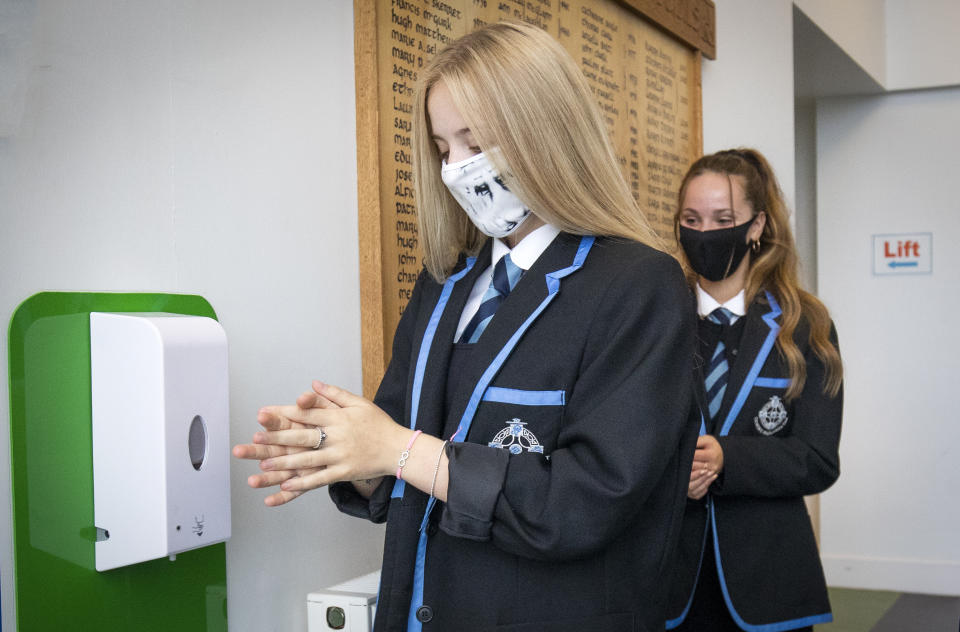 (left to right) Rebecca Ross and Sarah Watt, S4 students at St Columba's High School, Gourock, disinfect their hands and put on their protective face masks as the requirement for secondary school pupils to wear face coverings when moving around school comes into effect from today across Scotland.