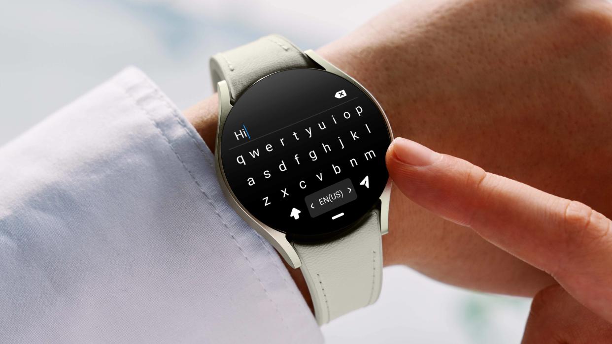  Samsung Galaxy Watch 6 worn on wrist with keyboard display screen. 