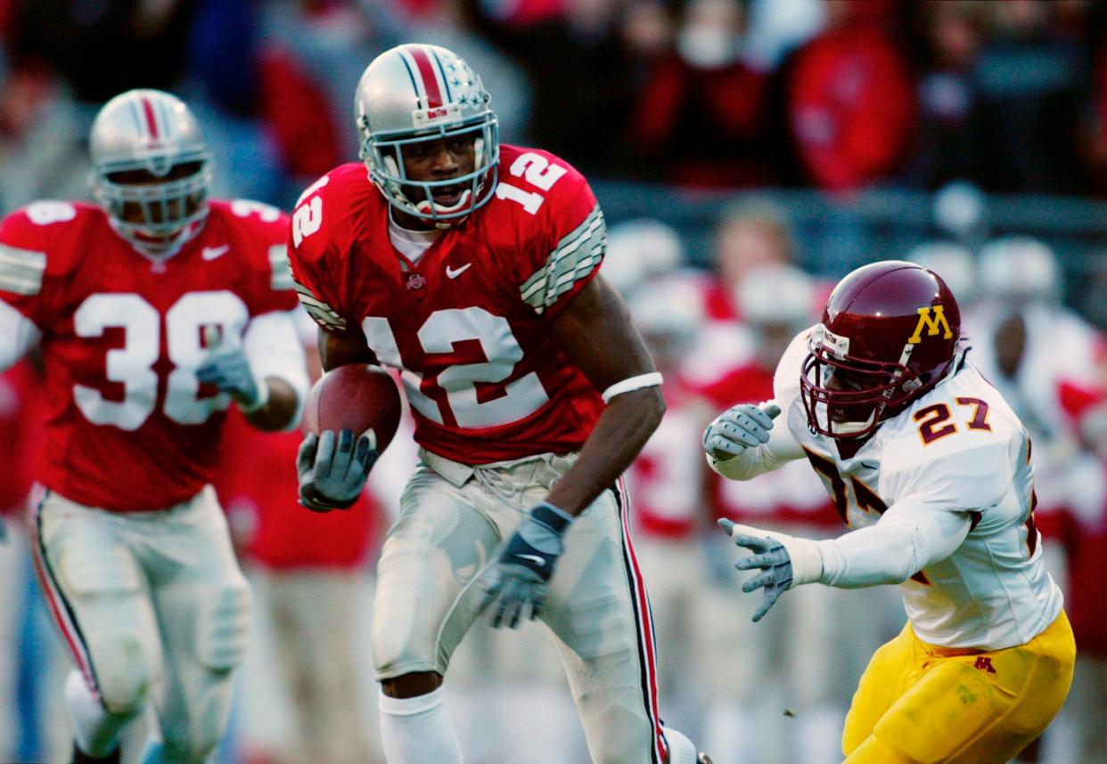 (MM OSUMIN MUNDEN 2NOV02) Ohio State's Michael Jenkins (cq) 12, slips by Minnesota's Eli Ward (cq) 27, after making a Krenzel reception in the second quarter of their game at The Ohio Stadium, November 2, 2002. Jenkins gained 49 yards and set up the Lydell Ross touchdown. (Dispatch photo by Mike Munden)