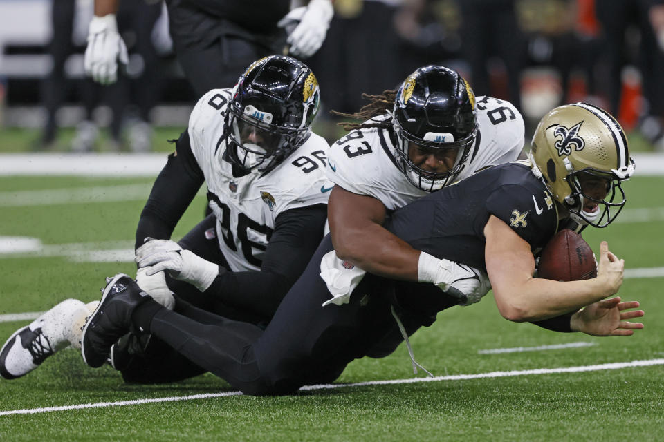 New Orleans Saints quarterback Derek Carr, right, is stopped by Jacksonville Jaguars defensive end Adam Gotsis (96) and defensive end Tyler Lacy (93) as he scrambled for yardage in the second half of an NFL football game in New Orleans, Thursday, Oct. 19, 2023. (AP Photo/Butch Dill)