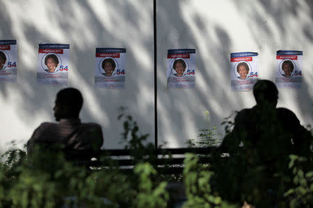 Men sit on a bench near electoral posters of presidential candidate Maryse Narcisse of Fanmi Lavalas party, in a park of Port-au-Prince, Haiti, November 16, 2016. REUTERS/Andres Martinez Casares