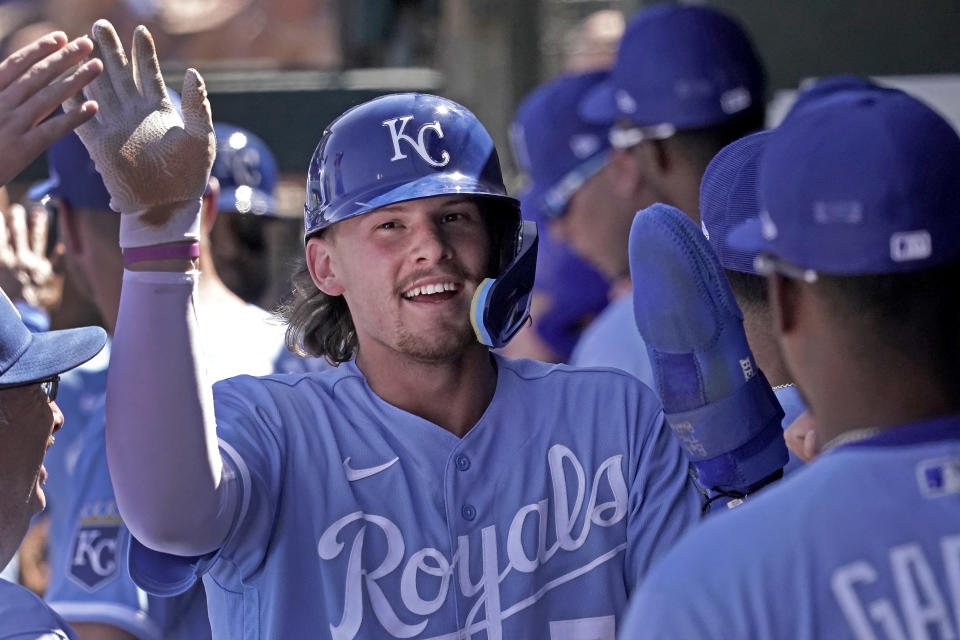 Kansas City Royals' Bobby Witt Jr. celebrates in the dugout after scoring on a sacrifice fly hit by Carlos Santana during the third inning of a spring training baseball game against the Cincinnati Reds Thursday, March 24, 2022, in Surprise, Ariz. (AP Photo/Charlie Riedel)