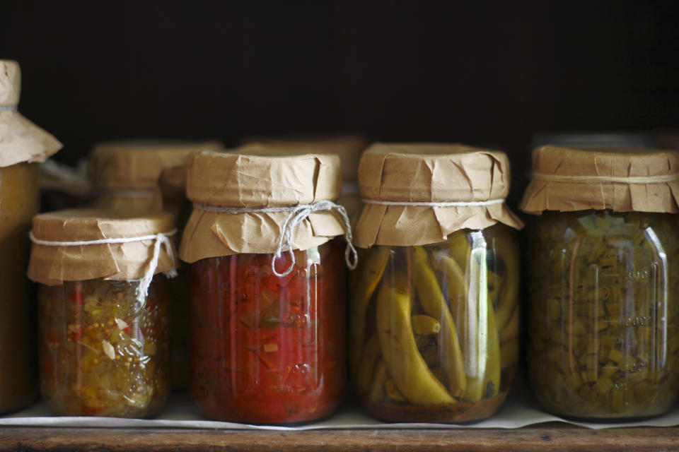 Row of canned vegetables in 19th century style canning jars with paper tops