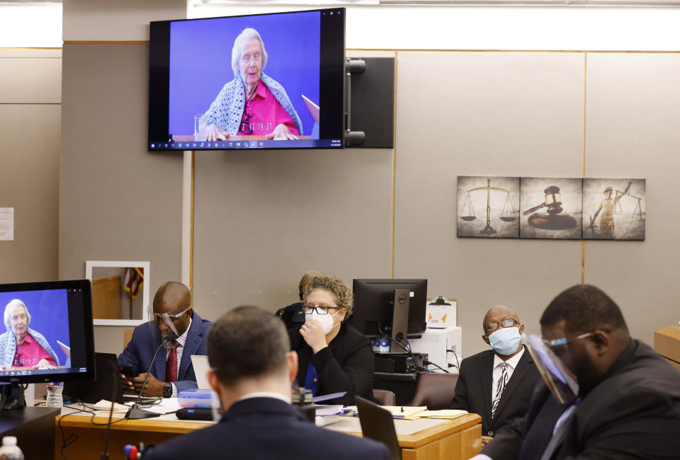 A recorded video deposition by victim Mary Bartel is shown to jurors as she responds to questions from the prosecutor and defense attorney during the murder trial of Billy Chemirmir, second from right, at the Frank Crowley Courts Building in Dallas, Monday, Nov. 15, 2021. Chemirmir is charged with killing 18 older women in Dallas and its suburbs over a two-year span. (Tom Fox/The Dallas Morning News via AP, Pool)