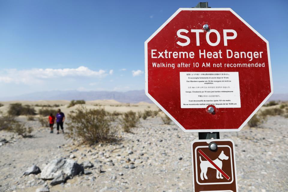 DEATH VALLEY NATIONAL PARK, CALIFORNIA - AUGUST 17: Visitors walk near a sign warning of extreme heat danger on August 17, 2020 in Death Valley National Park, California. The temperature reached 130 degrees at Death Valley National Park on August 16, hitting what may be the hottest temperature recorded on Earth since at least 1913, according to the National Weather Service. Park visitors have been warned, ‘Travel prepared to survive.’ (Photo by Mario Tama/Getty Images)