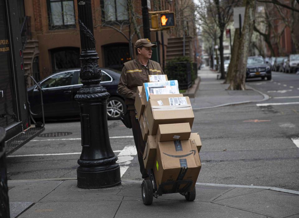 A delivery man for United Parcel Service, UPS, moves his hand truck loaded with packages through a residential neighborhood in Brooklyn, New York on March 30, 2020. 