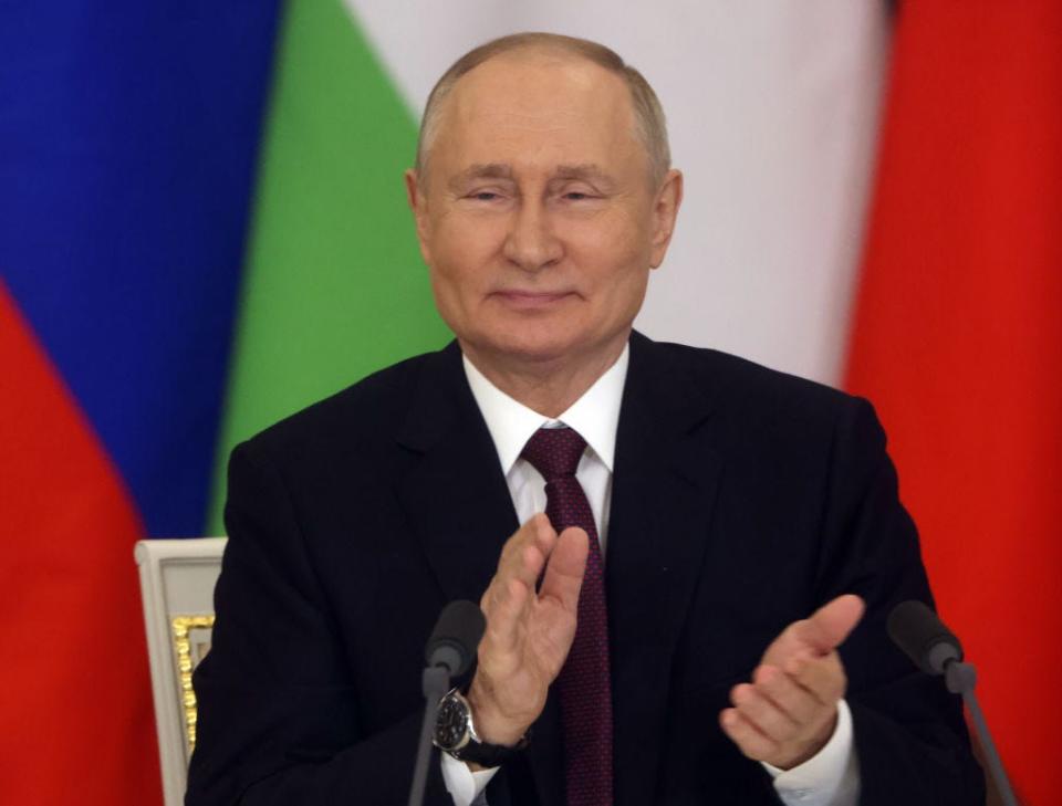 Russian President Vladimir Putin applauds.
