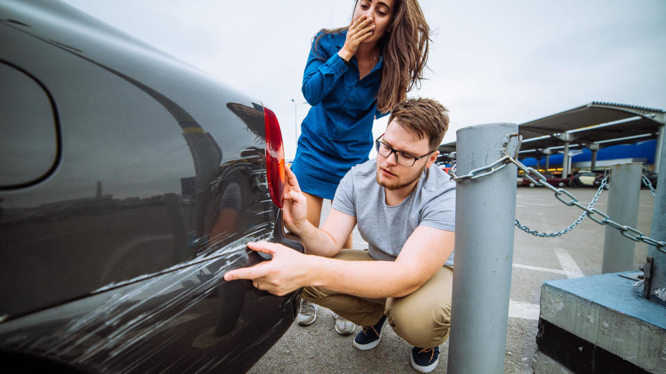 man with sad look on scratched car.