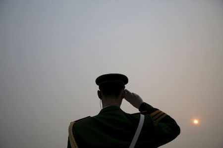 The sun is seen through smog on a severely polluted day as a paramilitary policeman salutes to delegates arriving to the Great Hall of the People ahead of Saturday's opening ceremony of the National People's Congress (NPC), in Beijing, China March 4, 2016. REUTERS/Damir Sagolj