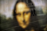 People walk past a reflection of the Mona Lisa in the Leonardo da Vinci museum, temporary closed due to the COVID-19 virus outbreak, in Venice, Saturday, Feb. 29, 2020. (AP Photo/Francisco Seco)