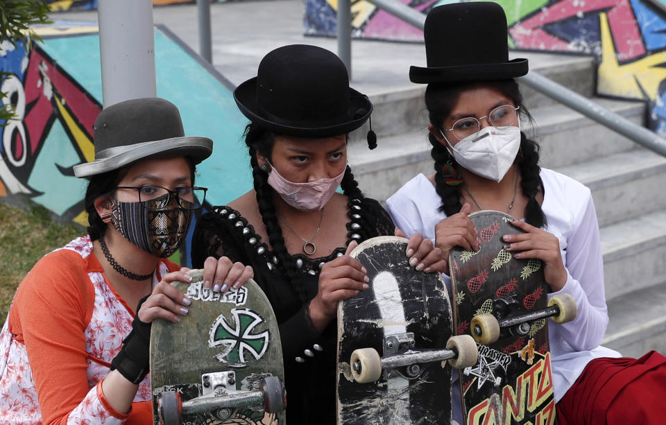 Yanira Villarreal, left, Ayde Choque, center, and Milenda Limachi, wearings masks amid the COVID-19 pandemic and dressed as a "Cholita" pose for a photo with their skateboards during a youth talent show in La Paz, Bolivia, Wednesday, Sept. 30, 2020. Young women called "Skates Imillas," using the Aymara word for girl Imilla, use traditional Indigenous clothing as a statement of pride of their Indigenous culture while playing riding their skateboards. (AP Photo/Juan Karita)