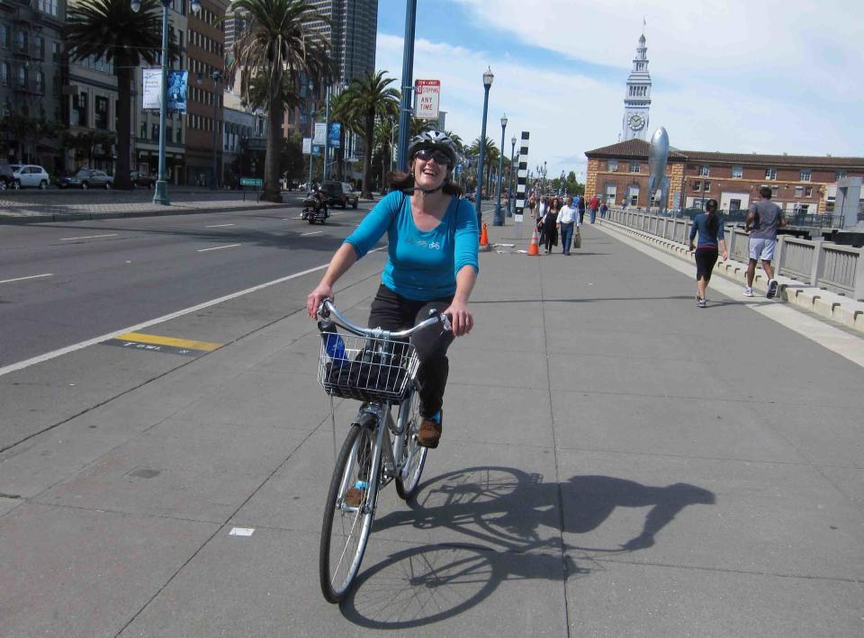 This October 2011 photo released by Tim McCarthy shows Paula Froke, of New York, riding along the Embarcadero in San Francisco during a Streets of San Francisco bike tour. Streets of San Francisco Bike Tours, launched in early 2011 by a group of friends who are passionate about both San Francisco and bicycles, and who'd worked as travel guides internationally before returning home to lead their own tours. (AP Photo/Tim McCarthy)