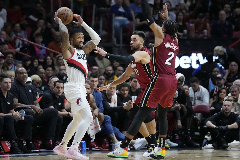 Portland Trail Blazers guard Damian Lillard, left, looks for an open teammate past Miami Heat guards Gabe Vincent (2) and Max Strus (31) during the second half of an NBA basketball game, Monday, Nov. 7, 2022, in Miami. (AP Photo/Wilfredo Lee)