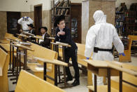 Policías con trajes especiales irrumpen en una sinagoga de Bnei Brak, suburbio ultraortodoxo de Tel Aviv cuyos residentes resisten las medidas del gobierno israelí para contener la propagación del coronavirus. (AP Photo/Ariel Schalit, File )