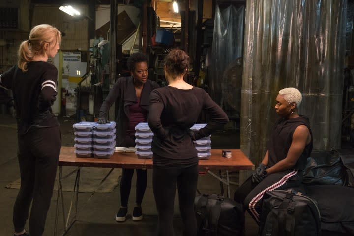 Elizabeth Debicki, Michelle Rodriguez, Viola Davis, and Cynthia Erivo sit and stand in a warehouse together in Widows.