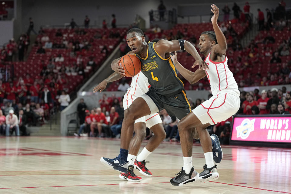 North Carolina A&T forward Marcus Watson (4) bursts through a double-team by Houston guards Tramon Mark (12) and Jamal Shead (rear) during the first half of an NCAA college basketball game, Tuesday, Dec. 13, 2022, in Houston. (AP Photo/Kevin M. Cox)