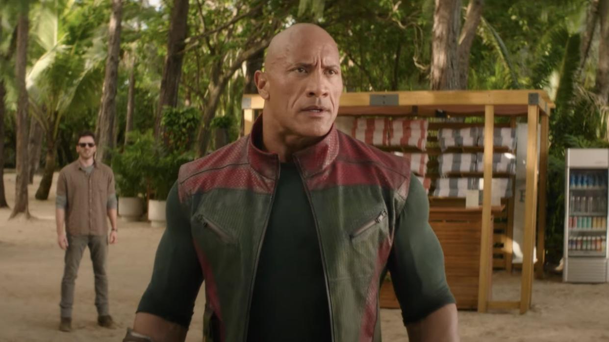  Dwayne Johnson stands ready for battle on a beach, while Chris Evans hangs back in the distance in Red One. 