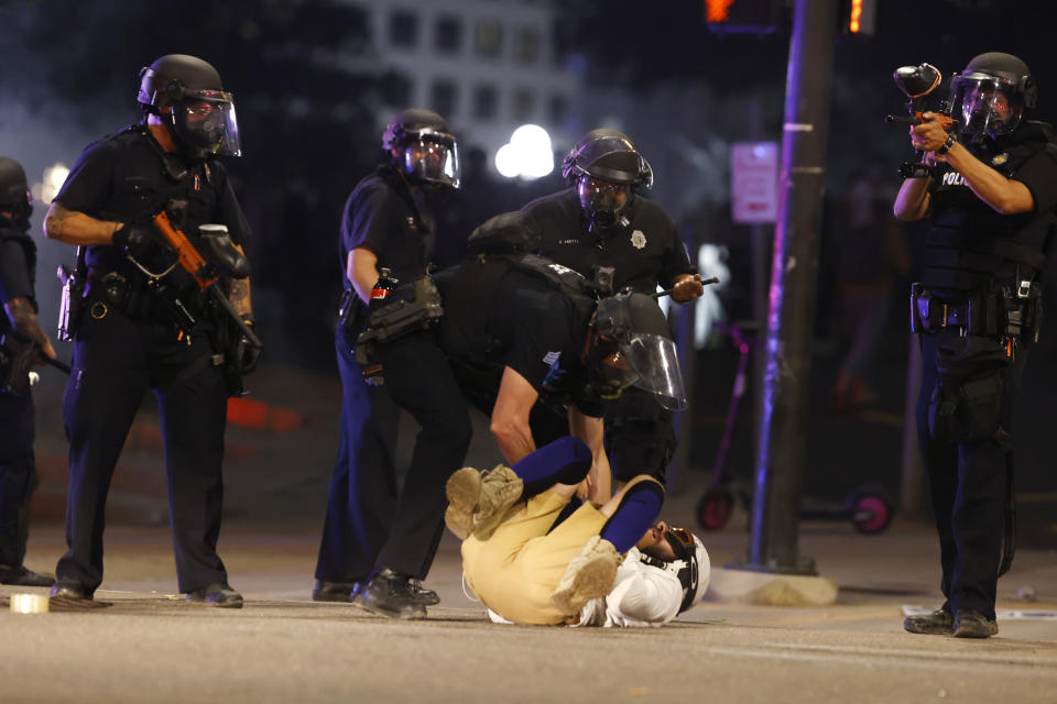 Denver Police Department officers stand over a man who fell to the street after they used tear gas and rubber bullets to disperse a protest outside the State Capitol over the death of George Floyd, a handcuffed black man who died in police custody in Minneapolis, late Thursday, May 28, 2020, in Denver. (AP Photo/David Zalubowski)