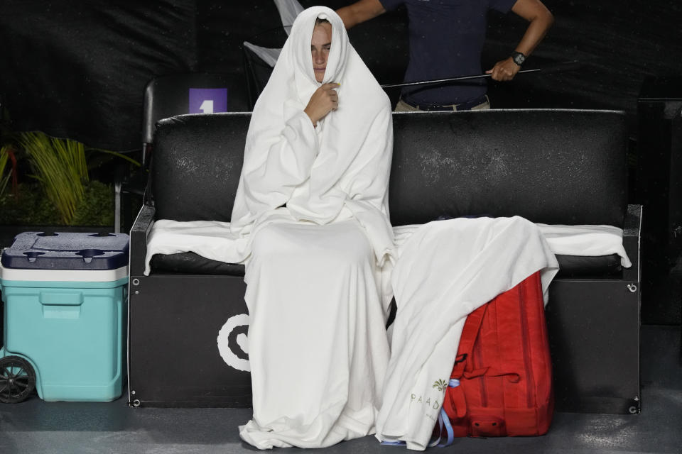La bielorrusa Aryna Sabalenka se envuelve en una toalla mientras espera la reanudación de una semifinal del torneo de la WTA en Cancún, México, interrumpido por la lluvia el 4 de noviembre de 2023 (AP Foto/Fernando Llano).