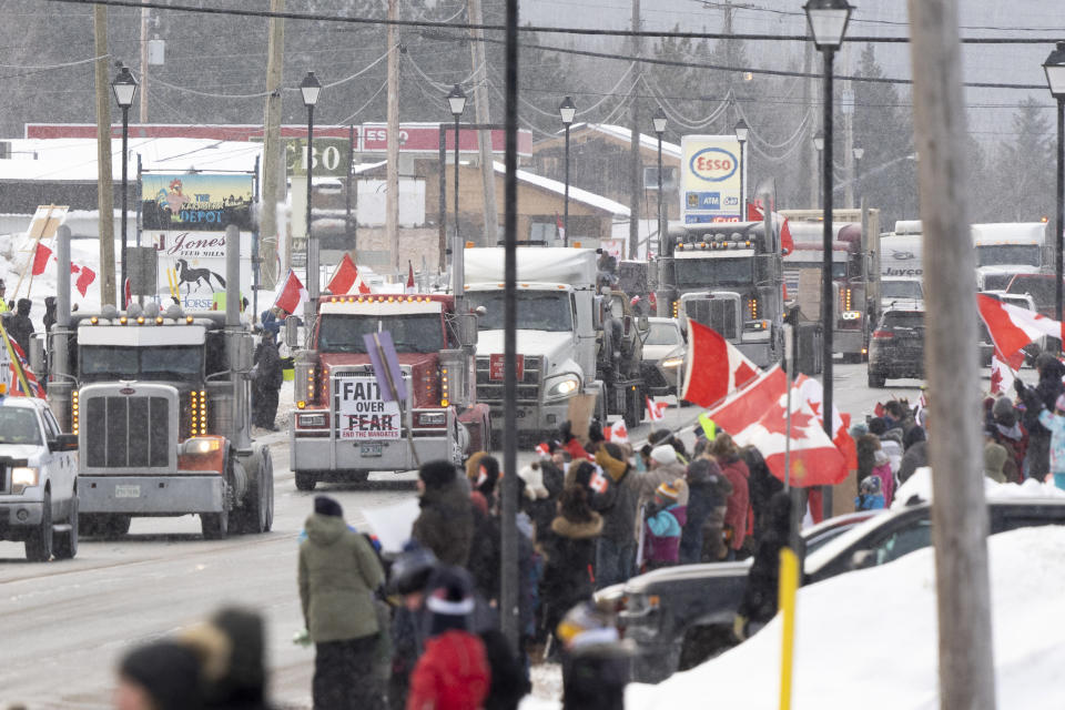 Protesters and supporters against a COVID-19 vaccine mandate for cross-border truckers cheer as a parade of trucks and vehicles pass through Kakabeka Falls outside of Thunder Bay, Ontario, on Wednesday, Jan. 26, 2022. (David Jackson/The Canadian Press via AP)