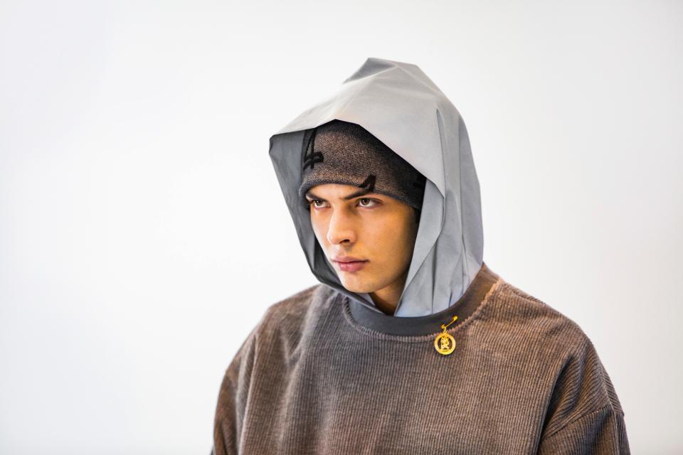 A brooch-embellished sweatshirt with reflective hood from the 4S Designs Fall/Winter 2021 collection.