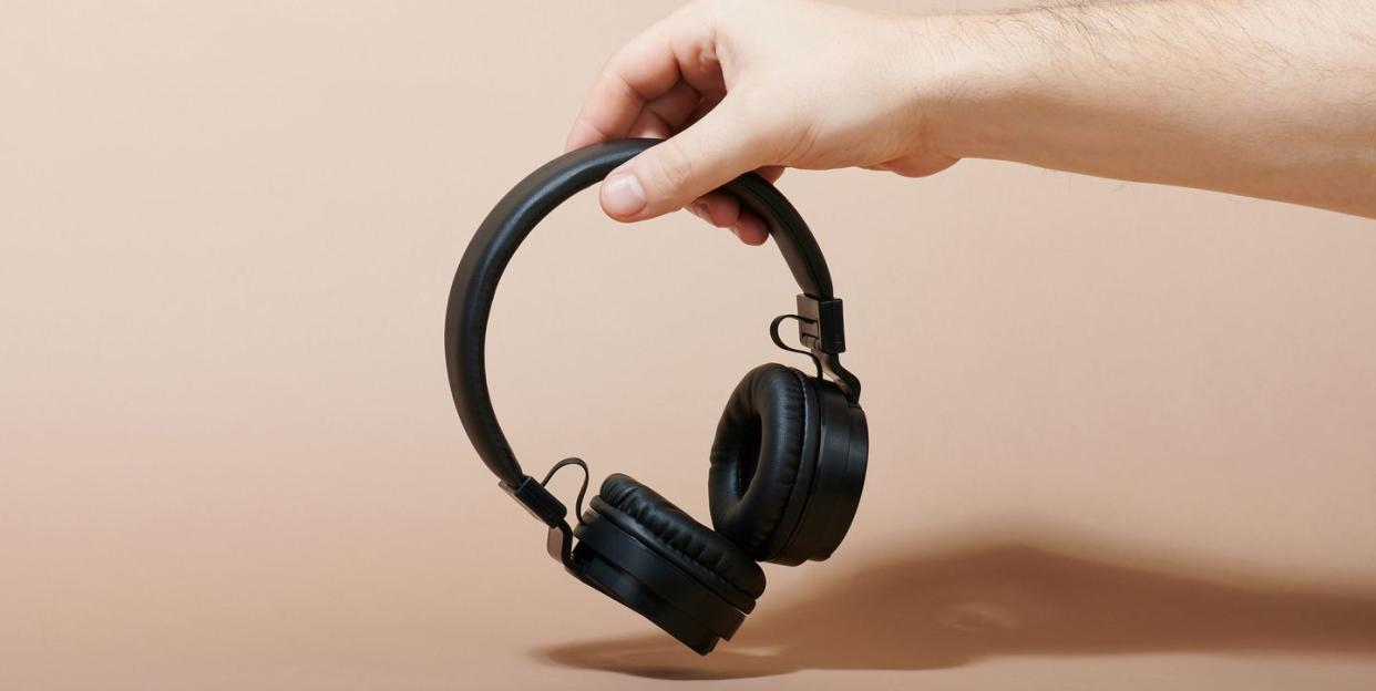 man's hand holding black headphones