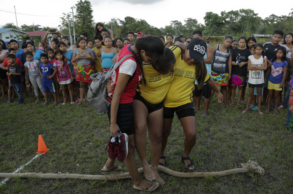 In this Nov. 25, 2018 photo, an injured Guna woman is aid by her teammates after the tug-of-war competition of the second edition of the Panamanian indigenous games in Piriati, Panama. Events such as archery, swimming, wrestling and running are also a part of the games. (AP Photo/Arnulfo Franco)