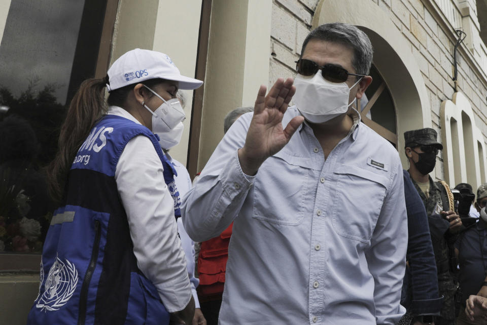 El presidente de Honduras, Juan Orlando Hernández, saluda tras llegar a una base aérea en Tegucigalpa, Honduras, el sábado 13 de marzo del 2021. (AP Photo/Elmer Martinez)