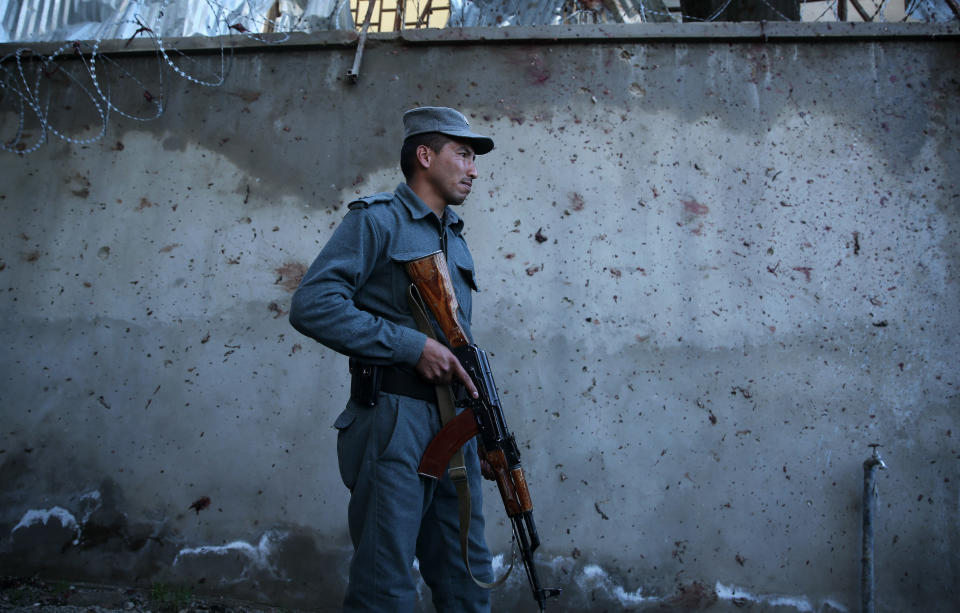 An Afghan policeman stands guard after the Taliban launched an assault with a suicide bomber detonating his vehicle outside an election office in Kabul, Afghanistan, Tuesday, March 25, 2014. Gunmen stormed into the building, trapping dozens of employees inside and killing many. A candidate for a seat on a provincial council was among those killed, along with an election worker, a civilian and a policeman. (AP Photo/Massoud Hossaini)