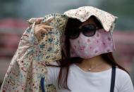 A woman wearing a face mask shields her face from the sun as haze shrouds Singapore August 26, 2016. REUTERS/Edgar Su