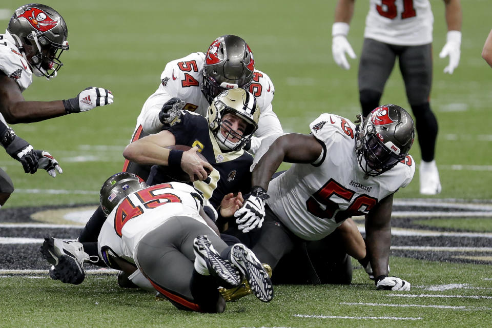 New Orleans Saints quarterback Drew Brees, center, is tackled between Tampa Bay Buccaneers' Devin White (45), Lavonte David (54) and Rakeem Nunez-Roches (56) during the first half of an NFL divisional round playoff football game, Sunday, Jan. 17, 2021, in New Orleans. (AP Photo/Brett Duke)