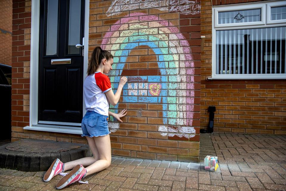 A teenager draws a rainbow and an NHS logo on the wall of her house in Liverpool in support of the NHS as the UK continues in lockdown to help curb the spread of the coronavirus.