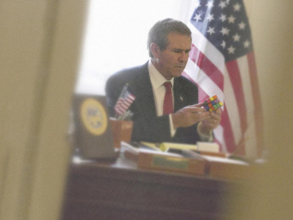 The photograph "Bush Rubik" shows a George W. Bush look-alike playing with a Rubik's Cube.