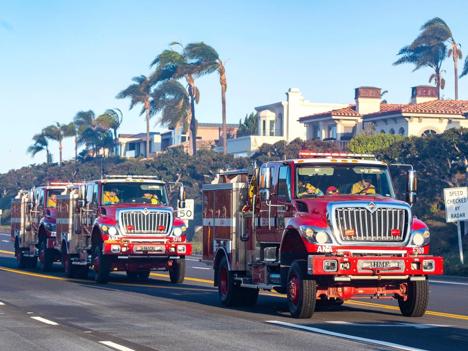 Firefighter trucks drive along the Pacific Coast Highway.