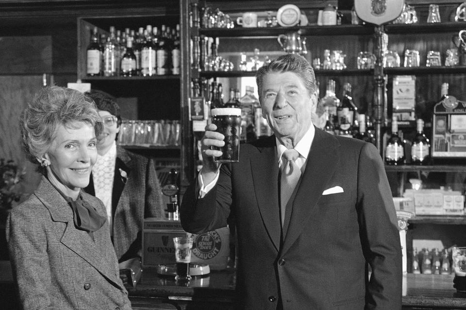 President Ronald Reagan toasts with a glass of Irish stout as he stands with wife, Nancy Reagan, at the bar of O'Farrell's Pub in the center of the village of Ballyporeen, Sunday, June 3, 1984, Ireland.