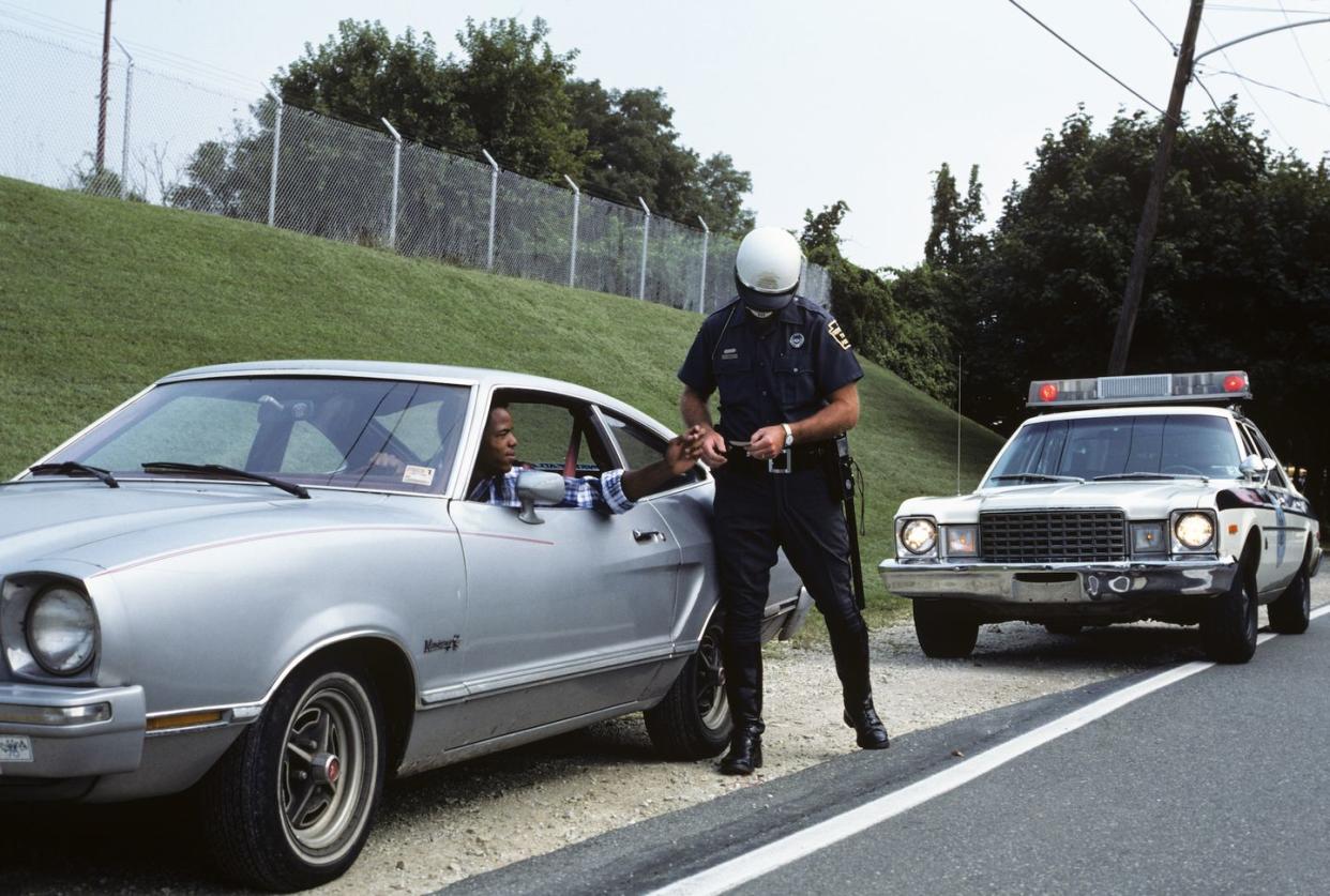1970s police officer checking drivers license of african american driver on side of road photo by h armstrong robertsclassicstockgetty images