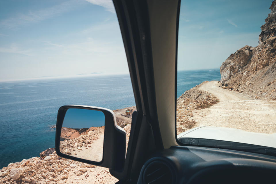 A car on a dirt road by the sea.