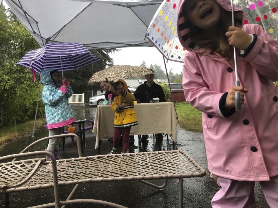 After a socially-distanced Rosh Hashanah supper with neighbors in Jennifer Fliss's Seattle driveway, her children played in the rain, as seen in this photo from Sept. 19, 2020. With COVID-19 still a threat, the family will likely have a similar celebration on Thanksgiving this year. (Jennifer Fliss via AP)