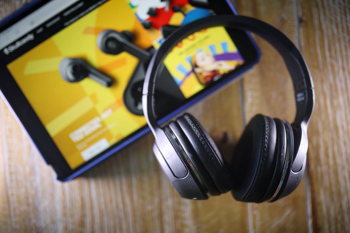 A pair of Skullcandy handy headphones sit on a table with an iPad.