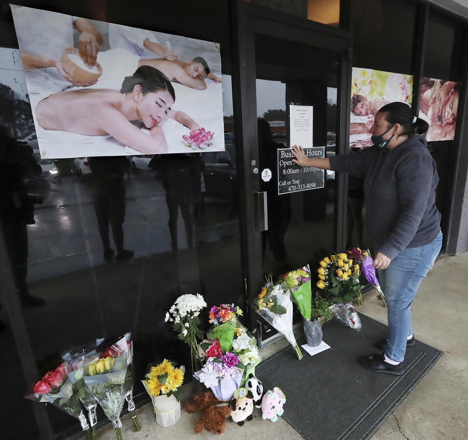 Jessica Lang pauses and places her hand on the door in a moment of grief after dropping off flowers at Youngs Asian Massage parlor where four people were killed, Wednesday, March 17, 2021, in Acworth, Ga. Lang, a local resident who lives nearby, said she knew one of the victims. A white gunman was charged Wednesday with killing eight people at three Atlanta-area massage parlors on Tuesday in an attack that sent terror through the Asian American community that’s increasingly been targeted during the coronavirus pandemic. (Curtis Compton/Atlanta Journal-Constitution via AP)