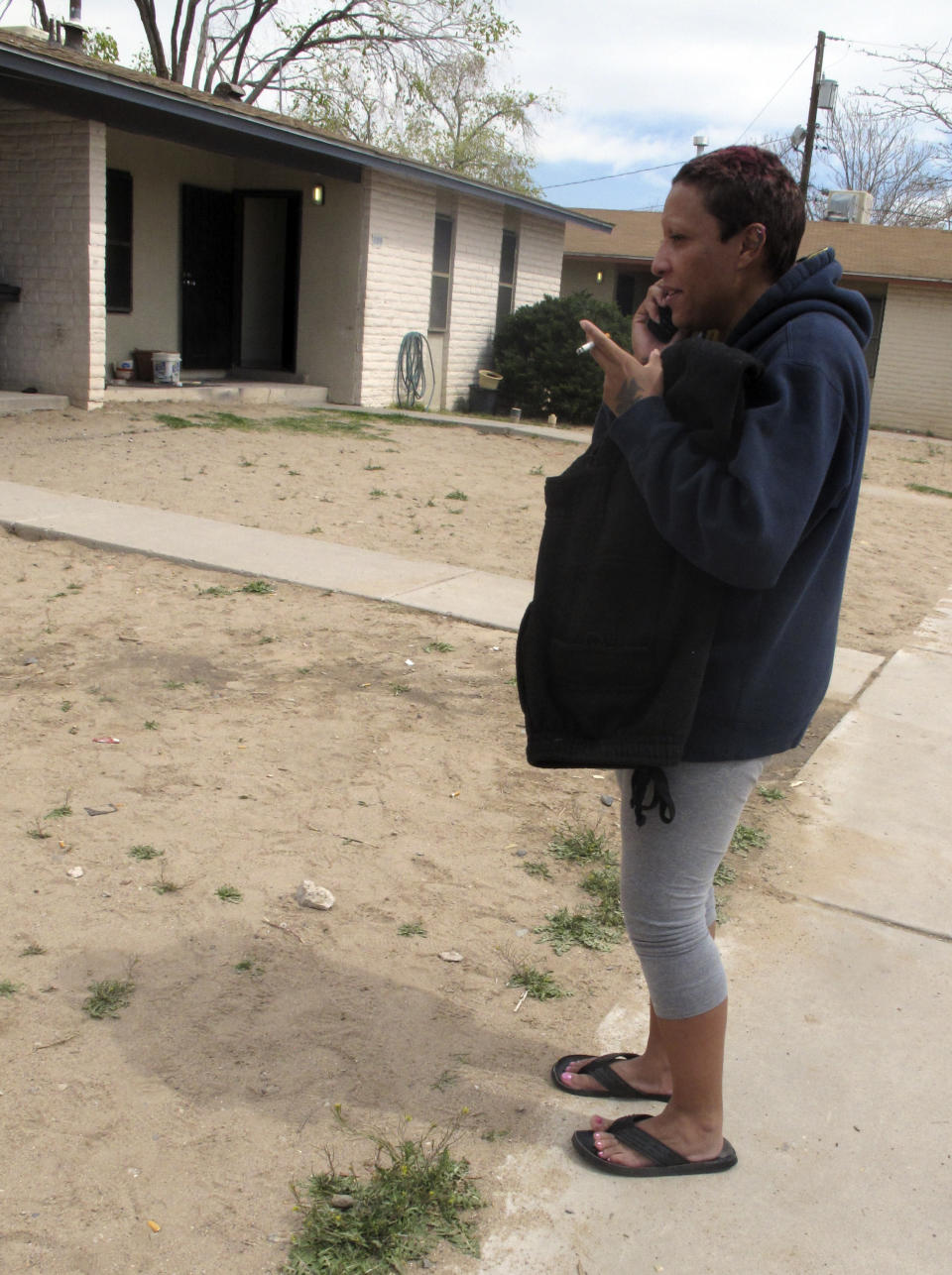 Tammy Redwine, 34, talks to a family member on Wednesday, March 26, 2014, at the site where Albuquerque police fatally shot her brother, Alfred "Lionel" Redwine, 30, at the public housing complex in Albuquerque, N.M. The embattled Albuquerque Police Department said officers shot and killed Redwine, who they say allegedly had a gun and opened fire on authorities, an account disputed by the man's family, who say Redwine was not armed and only had a cellphone in his hand. (AP Photo/Russell Contreras)