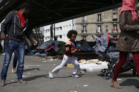 Migrants from Eritrea walk near tents as they live in a make-shift camp under a metro bridge in Paris, France, May 28, 2015. REUTERS/Benoit Tessier