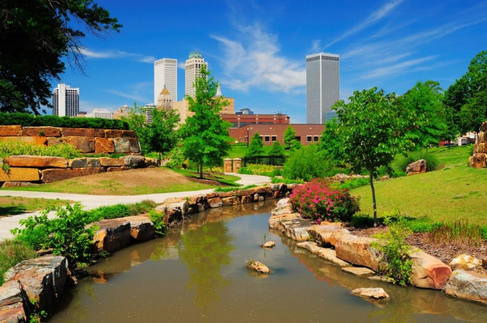 Park with stream grass and trees in front of skyline.