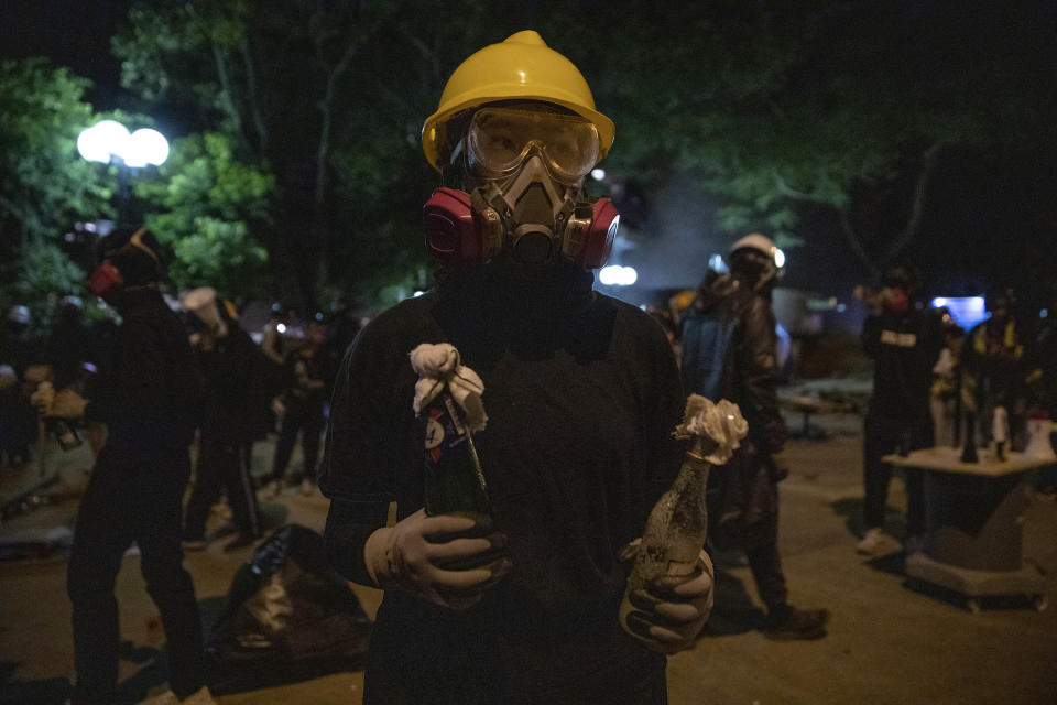 An anti-government protester holds two Molotov cocktail as she waits for the arrival of riot police outside the Hong Kong Polytechnic University in Hong Kong on Sunday, Nov. 17, 2019. Most anti-government protesters left Hong Kong's universities Saturday after occupying them for about a week. Small contingents that remained harassed some of those cleaning up and kept a major cross-harbor tunnel closed. (AP Photo/Ng Han Guan)