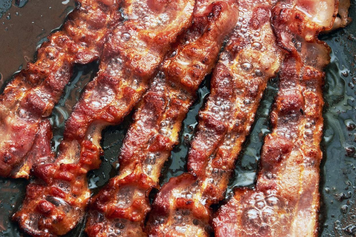 bacon slice being cooked in frying pan