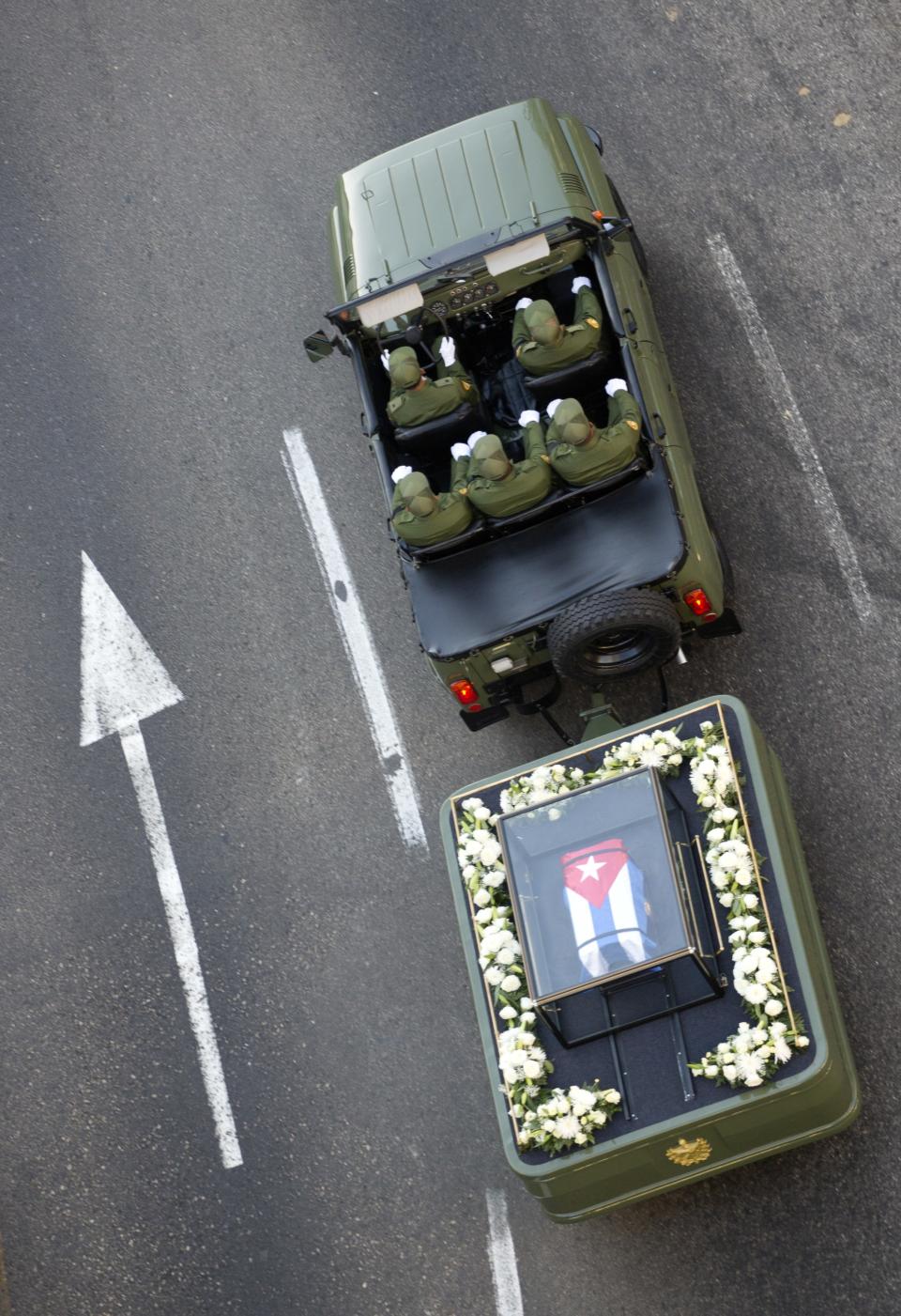 FILE - In this Nov. 30, 2016 file photo, a small, Cuban flag covered coffin containing the remains of Cuban leader Fidel Castro is pulled by a military vehicle through Havana, Cuba. Castro's ashes made a four-day journey across Cuba from Havana to their final resting place in the eastern city of Santiago. (AP Photo/Desmond Boylan, File)