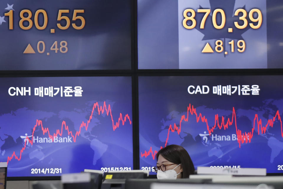 A currency trader watches computer monitors near the screens showing the foreign exchange rates at the foreign exchange dealing room in Seoul, South Korea, Friday, Jan. 15, 2021. Asian shares were mixed on Friday after a late slide in several Big Tech stocks left major indexes lower on Wall Street. (AP Photo/Lee Jin-man)