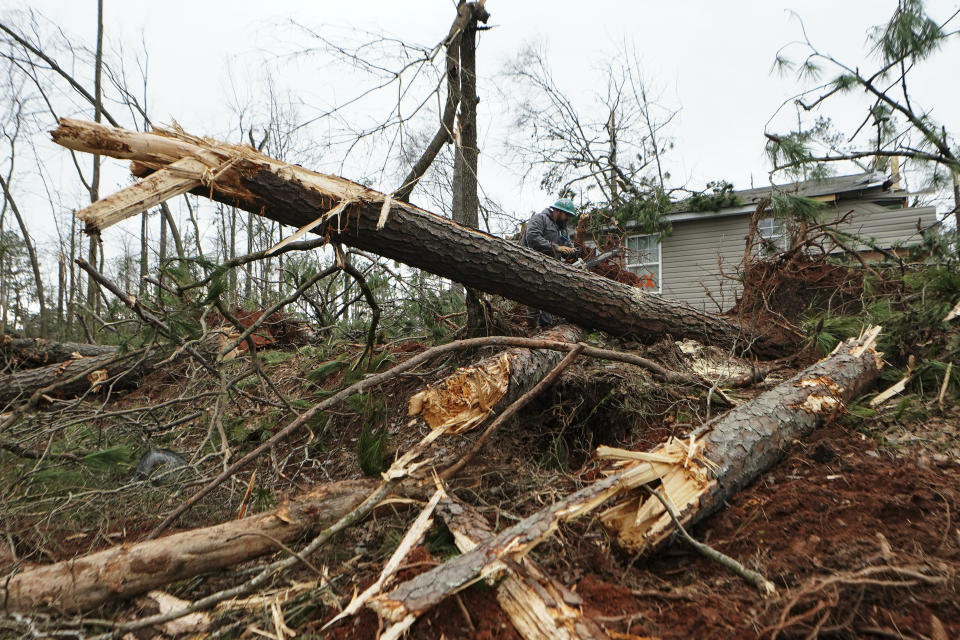 Joshua Jewell works to clear downed trees from around a storm damaged home Friday, Jan. 13, 2023, in Jackson, Ga. Powerful storms spawned tornadoes across Georgia Thursday night. (AP Photo/John Bazemore)